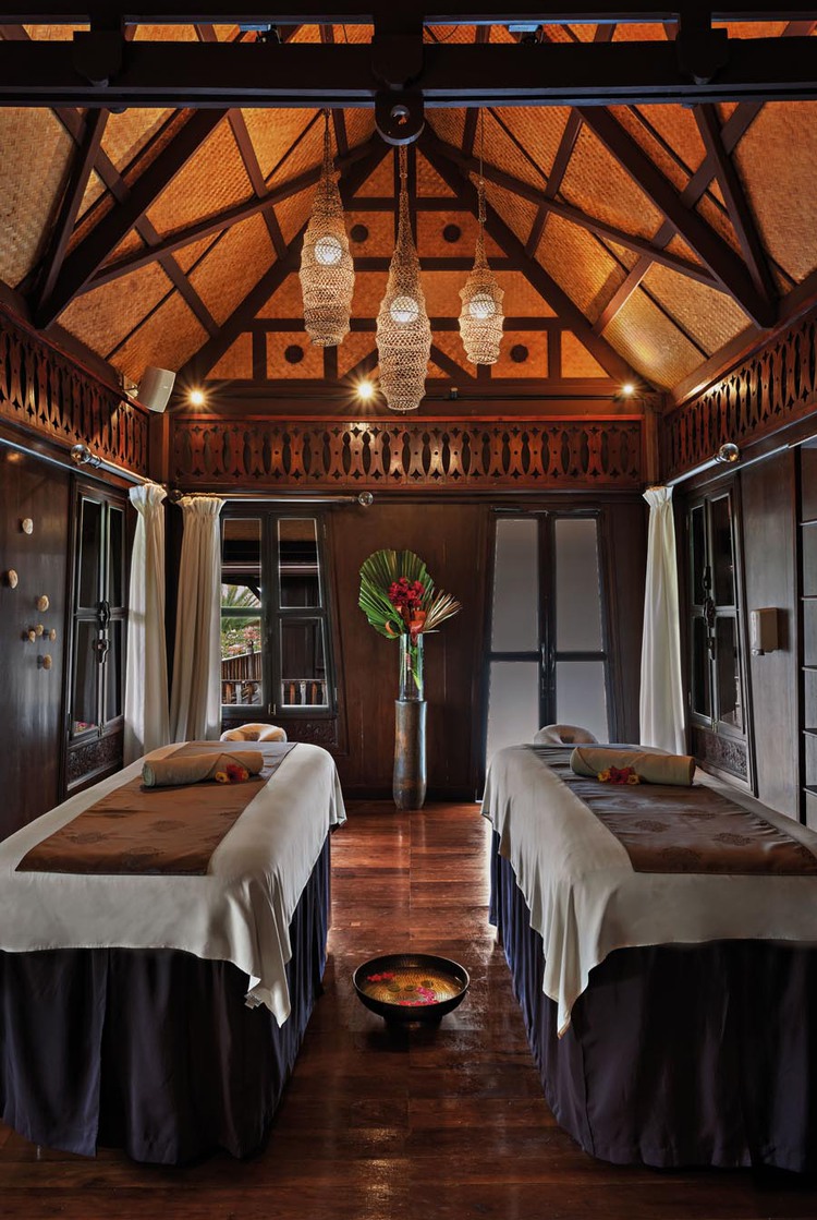Massage tables inside brown building with three hanging chandelier lights