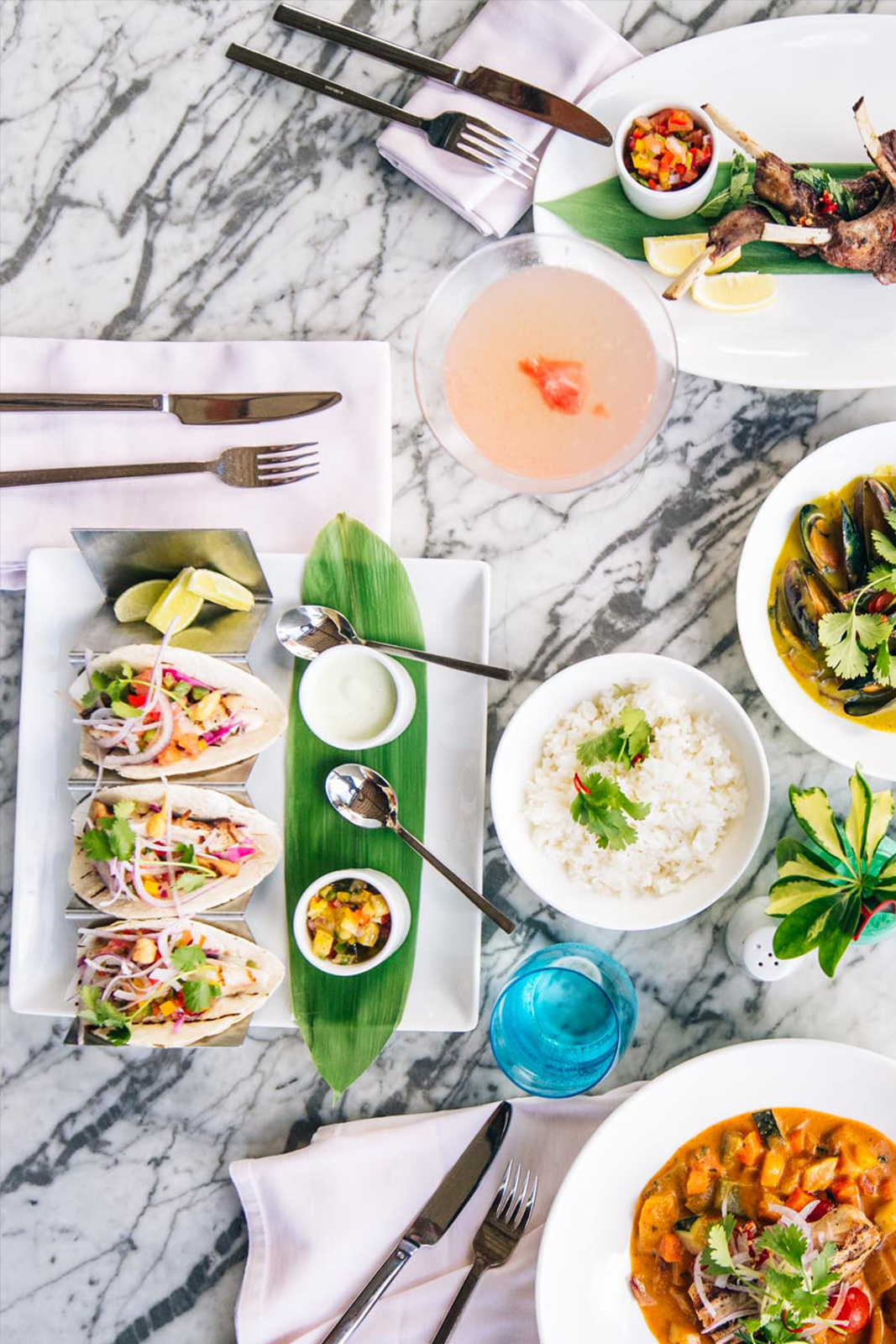 Tacos, curry e uma variedade de pratos na mesa de mármore branca