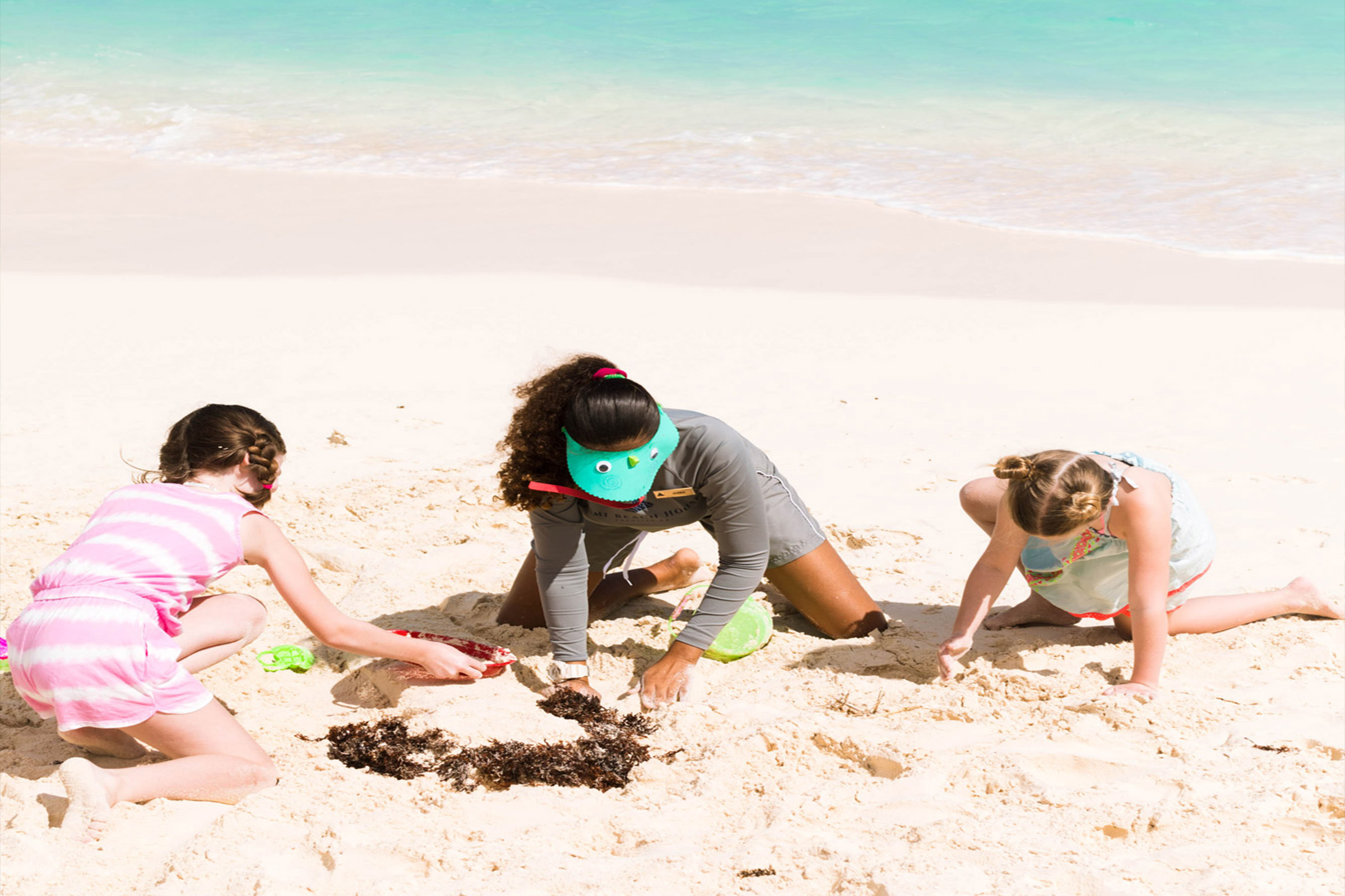 Donna e bambini che giocano nella sabbia