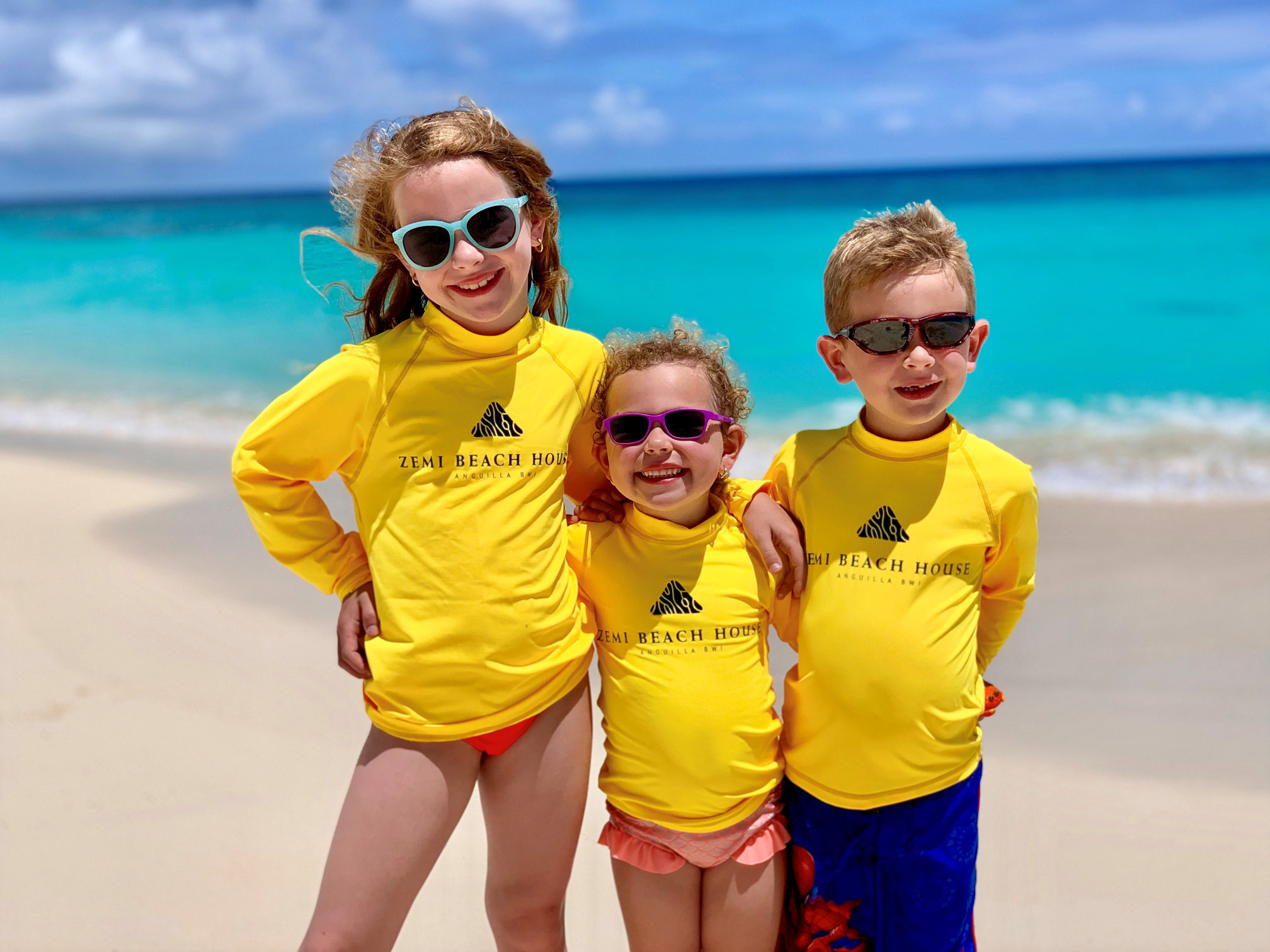 Kids posing at the beach wearing Zemi Beach House shirts