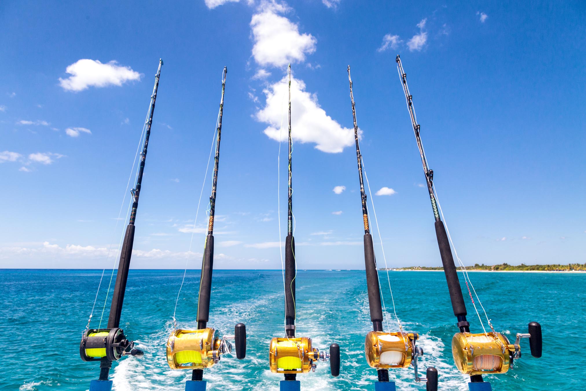 Cinco varas de pesca penduradas na extremidade traseira do barco no oceano