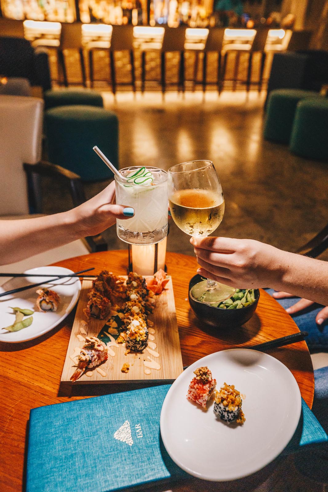 Duas mulheres desfrutando de sushi e bebidas à mesa